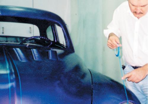 Here we’re setting the centerline for the headlight and left front fender design. Pull the tape back more than enough to another reference point you marked near the back of the fender. Set the same reference points on the opposite fender and repeat. Once the fender scallop lines on both fenders are finalized, remove the centerline tape. If your scallop or graphic is extremely radical, you may want to transfer it to the opposite fender via a paper pattern, as shown in steps 15 and 16.